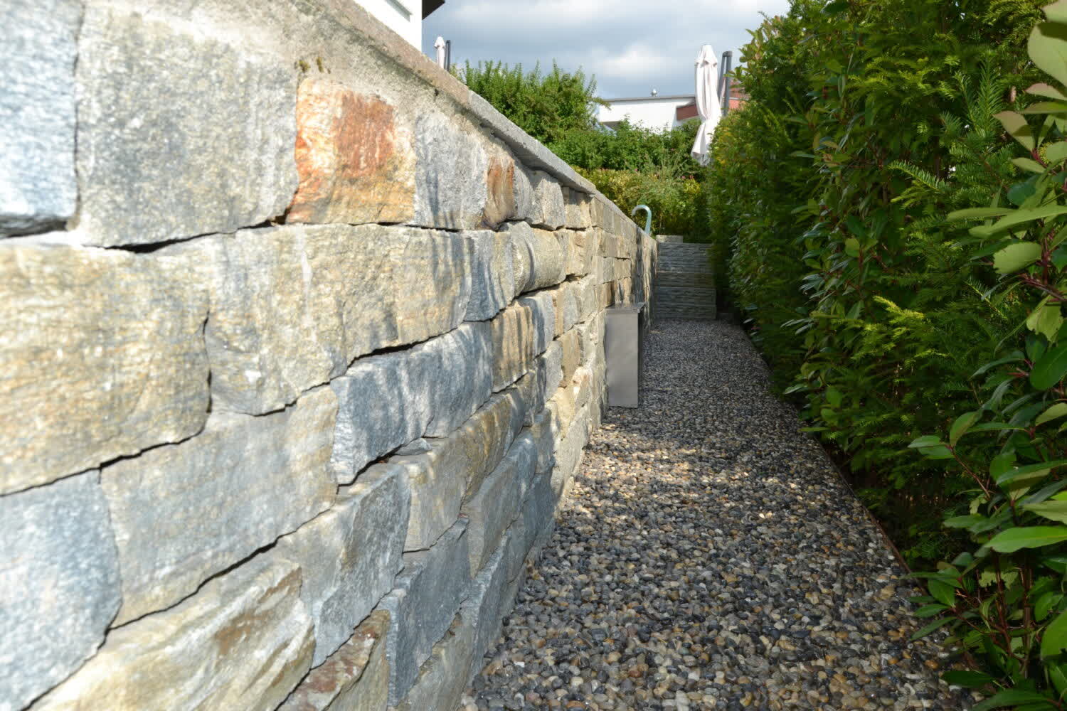 Natursteinmauer als Hangbefestigung im Garten, gebaut von Tahiri Gartenbau & Unterhalt GmbH